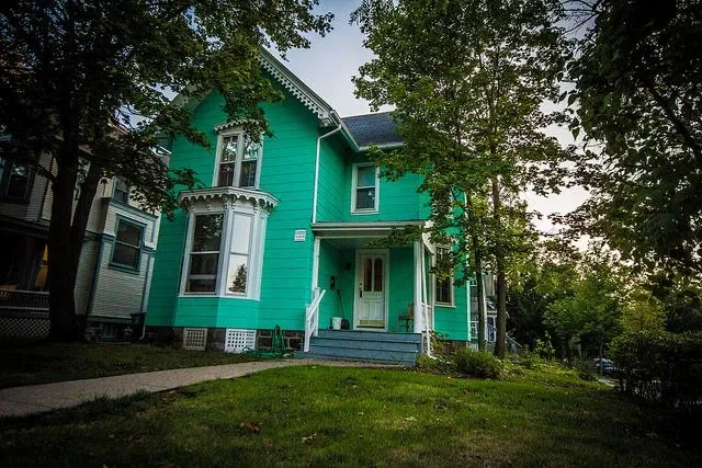 A bright green off-campus two story house.