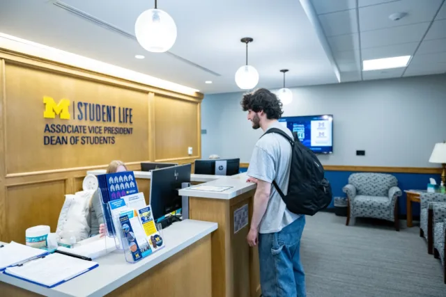 A student with light skin and a beard approached the desk at the Office of the Dean of Students.