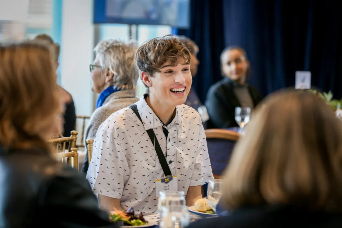 A student talking to a group of people while seated at a table at the Blavin Scholars celebration.