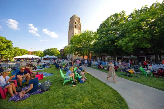 A large group of people gathered on Ingalls Mall near the Burton Memorial Tower on a summer day.
