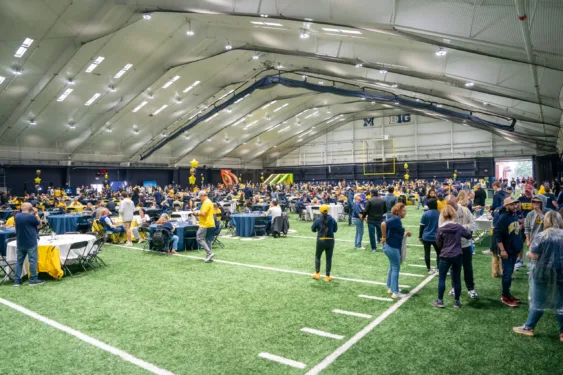 Students and their families gather on an indoor field for the Parents & Family Weekend Tailgate.