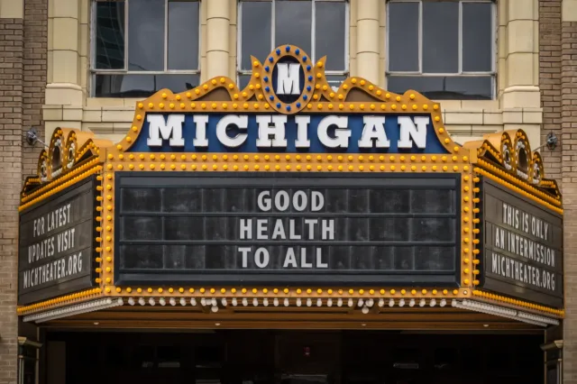 Michigan Theater marquee sign lit with bulbs reading “GOOD HEALTH TO ALL.”