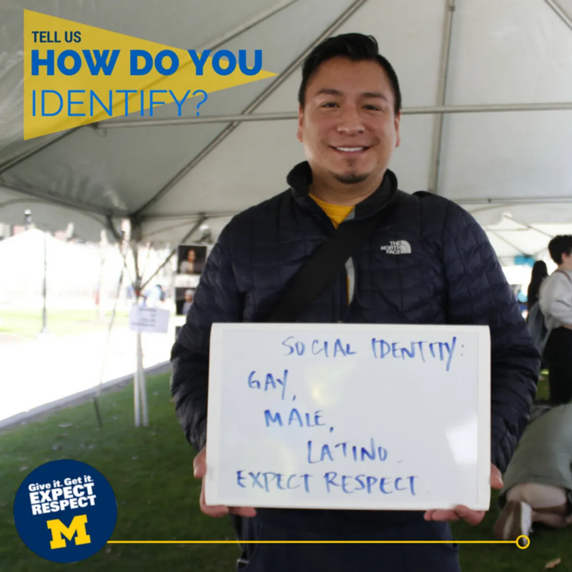 Photo of a student with medium dark skin, short black hair, and a goatee. In the upper left corner, a graphic reads How do you identify? The student is holding a sign that says Social Identity: Gay, Male, Latino, Expect Respect.